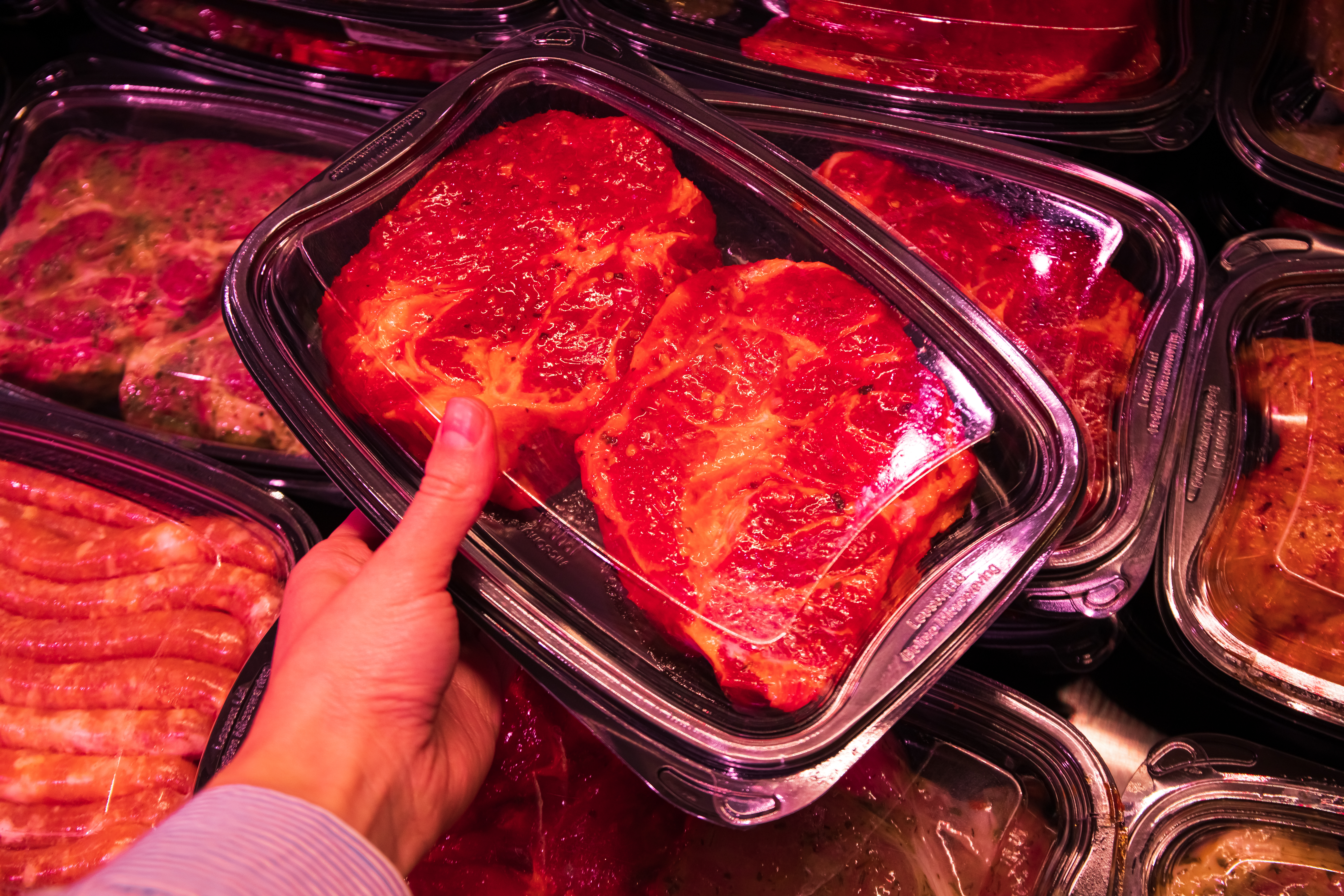 la mano de una mujer sosteniendo una bandeja de carne