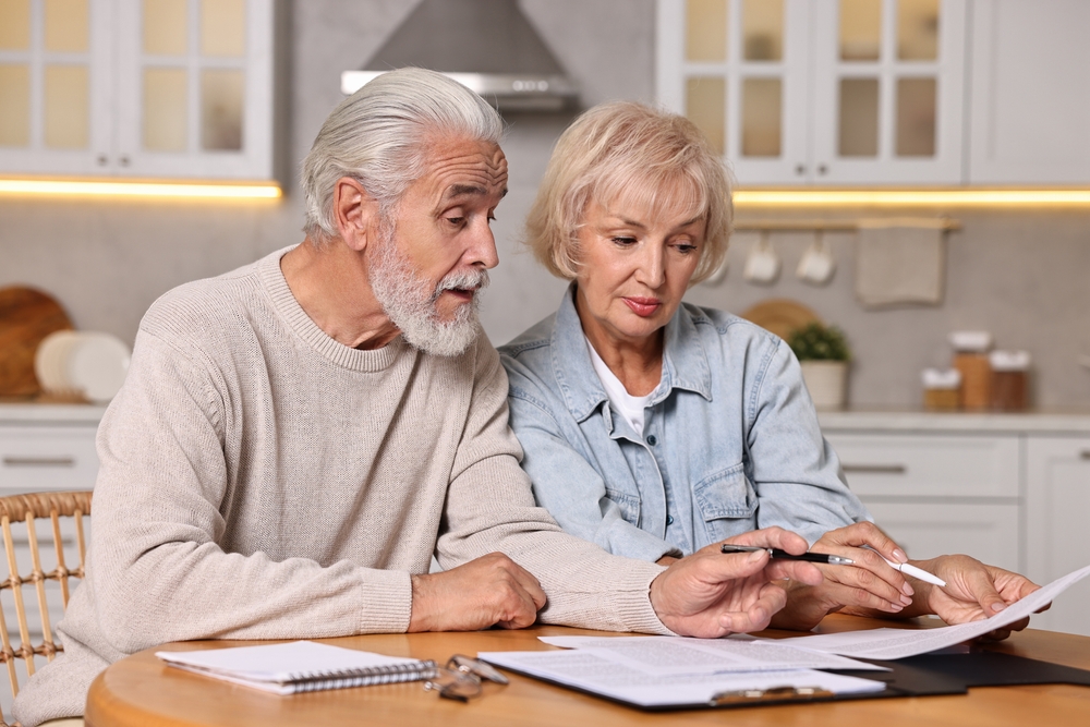 Ahorros de pensiones. Presupuesto de planificación de pareja senior en mesa de madera interior