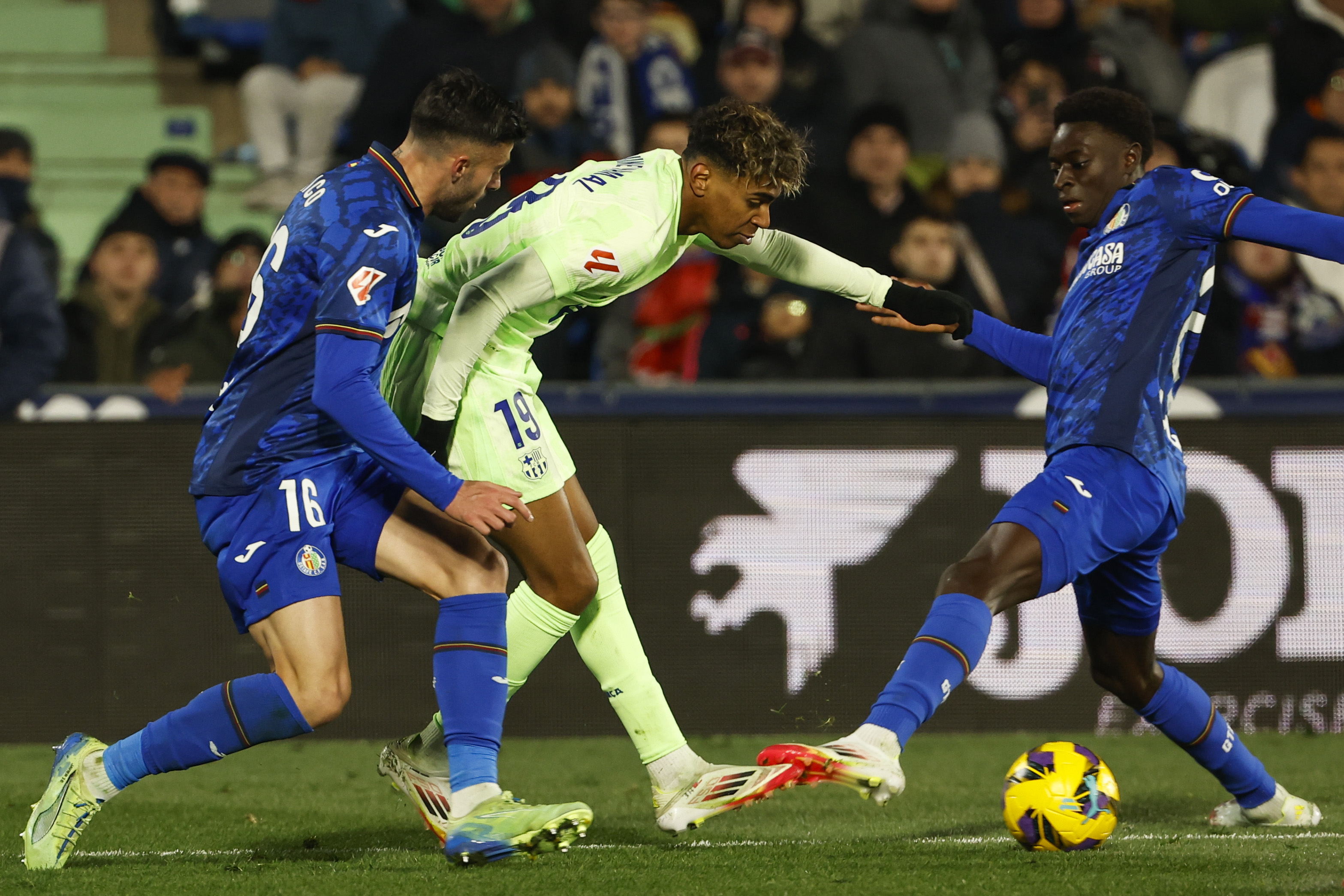 GETAFE (MADRID), 18/01/2025.- El delantero del Barcelona Lamine Yamal (c) juega un balón ante Diego Rico (i), del Getafe, durante el partido de LaLiga de fútbol que Getafe CF y FC Barcelona disputan este sábado en el Coliseum. EFE/Chema Moya