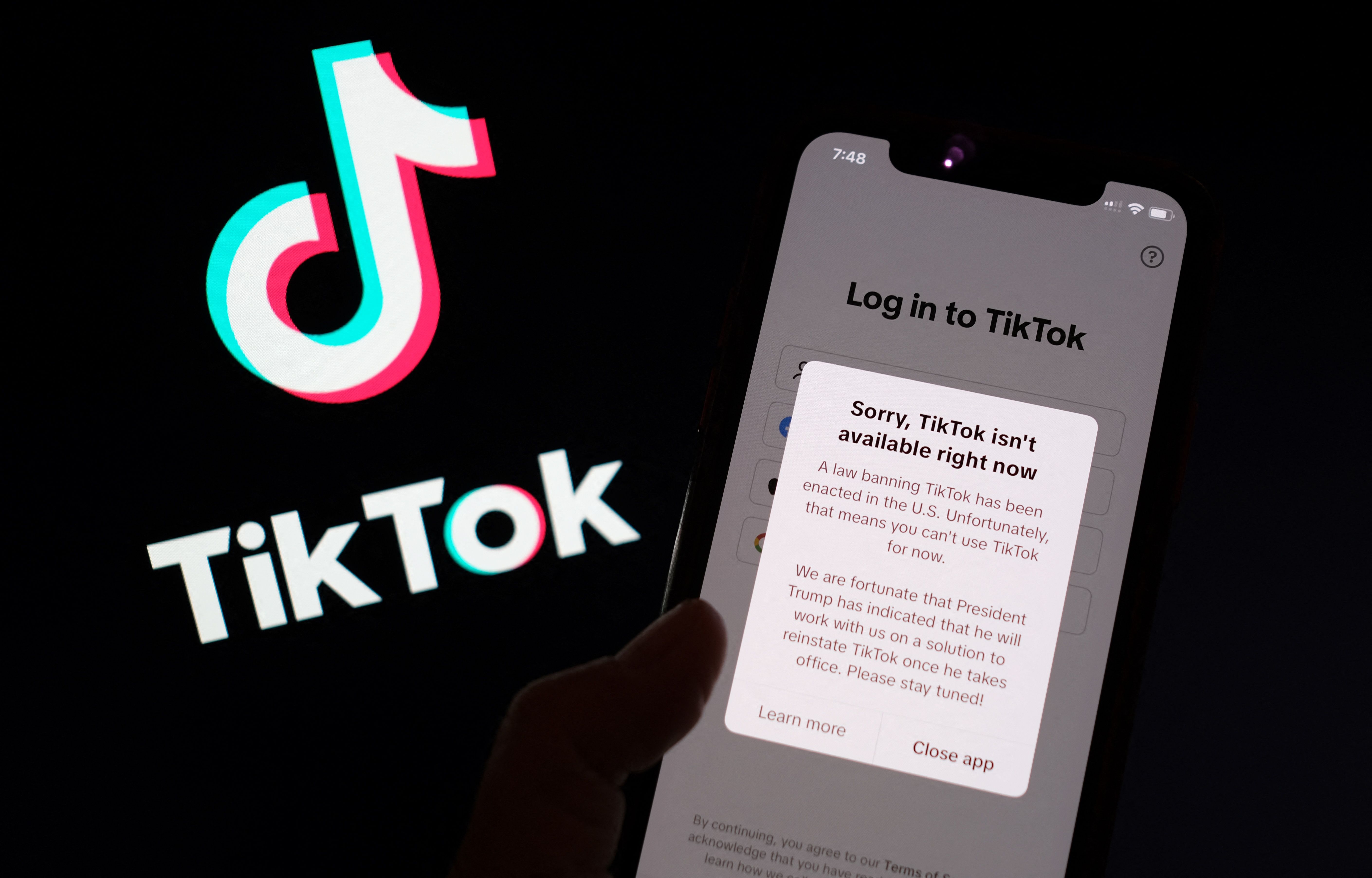 This illustration photo taken in Los Angeles on January 18, 2025, shows the TikTok app on a smartphone screen in front of the TikTok logo. TikTok disconnected access to its users in the United States late January 18 after no action was taken shortly before a national ban was to take effect, in the name of national security, unless its Chinese owners reach a deal to sell it to non-Chinese buyers by January 19, with President-elect Donald Trump unable to intervene until he takes office. "A law banning TikTok has been enacted in the US," said a message to users attempting to use the app. "Unfortunately, that means you can't use TikTok for now." (Photo by Chris DELMAS / AFP)