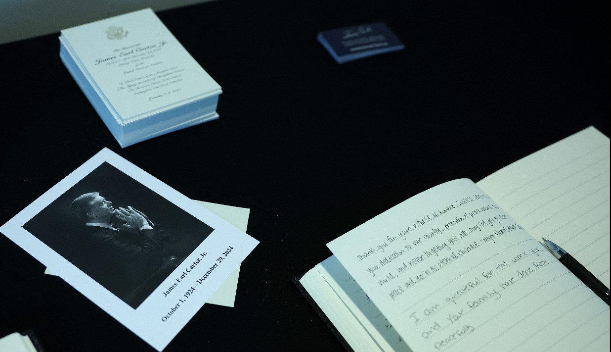 Un retrato de Jimmy Carter, junto al libro de condolencias, en el Capitolio, durante el funeral del expresidente. (Foto Prensa Libre: AFP)