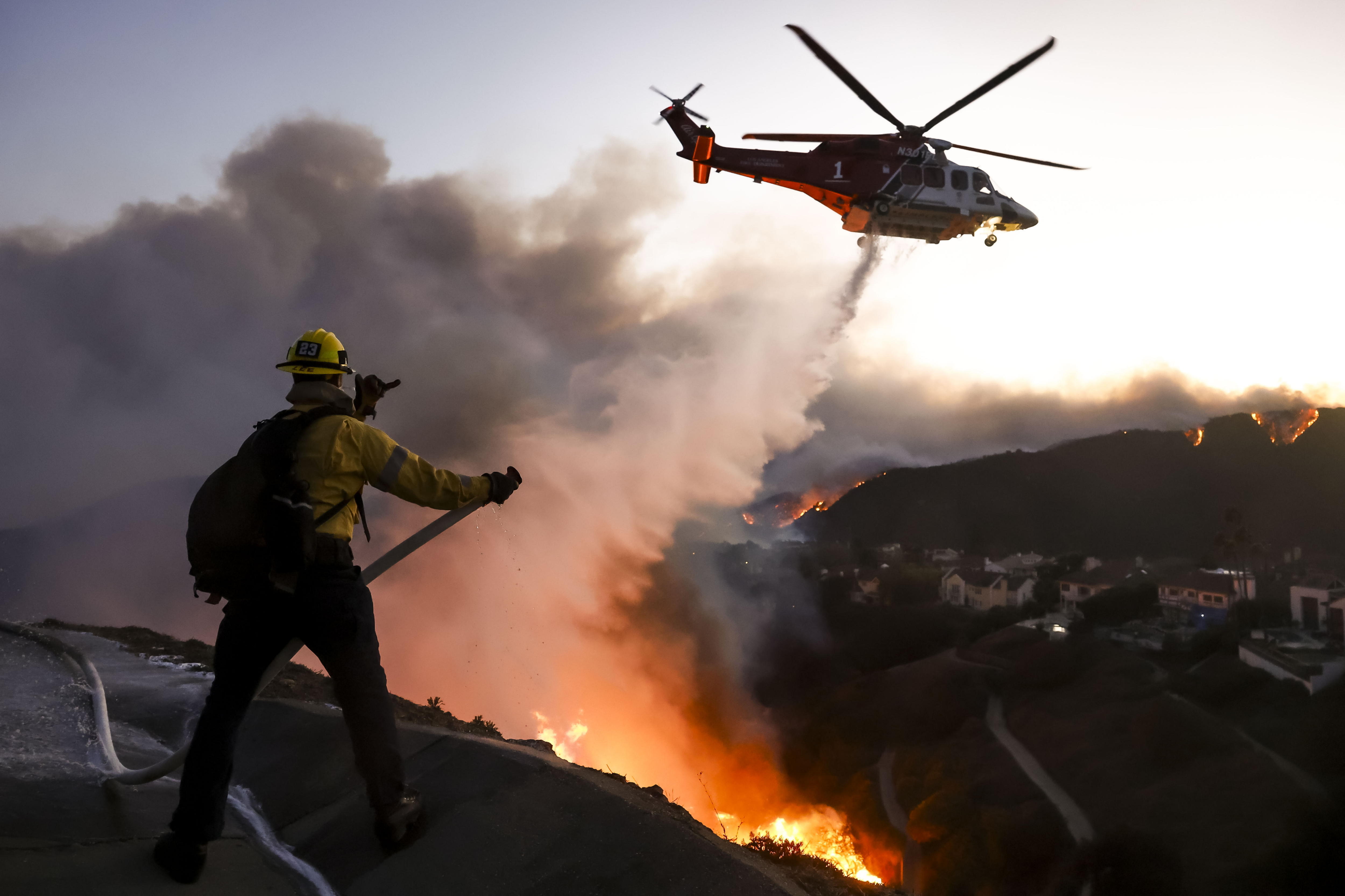 Pacific Palisades (United States), 07/01/2025.- Los Angeles County firefighters using hoses and water drops from a helicopter battle the Palisades wildfire in Pacific Palisades, California, USA, 07 January 2025. According to the National Weather Service, large portions of the Los Angeles area are under extreme wildfire risk from 07 to 08 January due to high winds and dry conditions. (incendio forestal) EFE/EPA/CAROLINE BREHMAN