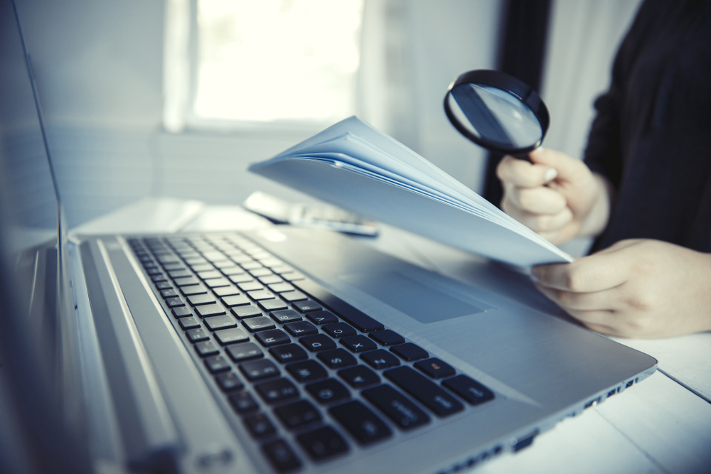 Woman holding magnifying glass over notebook, search concept. 