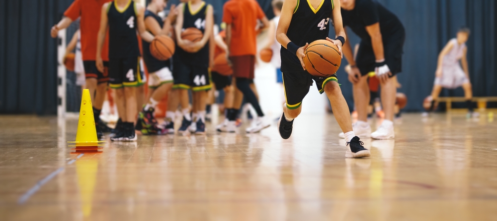 Jugadores de básquetbol jóvenes en un equipo de entrenamiento. Jóvenes Practican Baloncesto Con Entrenador Joven. Unidad De Capacitación En Baloncesto Para Jóvenes Jugadores