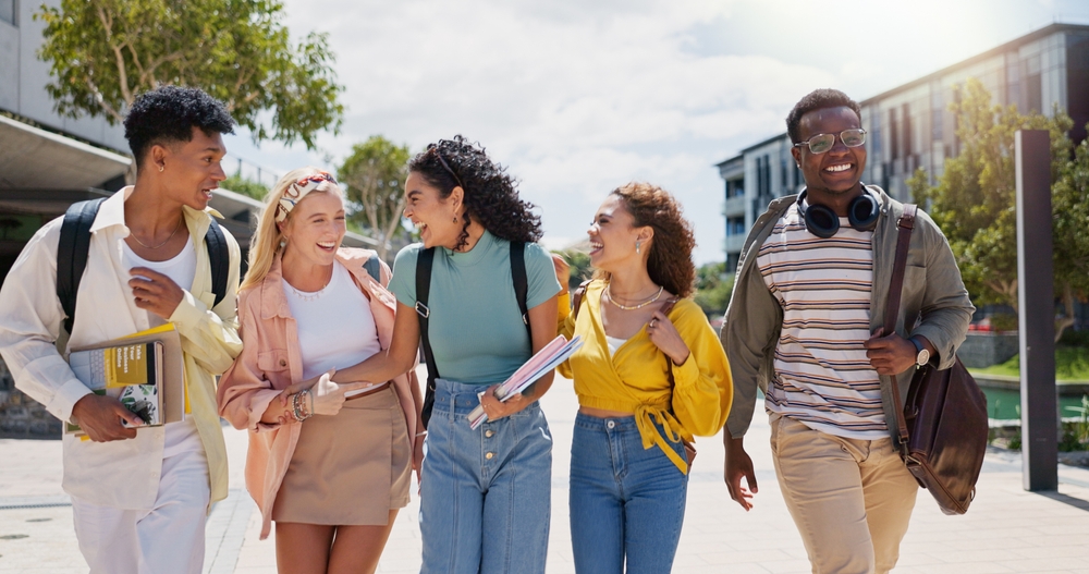 Feliz, universitario y conversación con amigos y diversidad de clases en el campus universitario con una sonrisa. Escuela, educación y estudiantes con broma y mochila al aire libre en la academia de aprendizaje con la gente