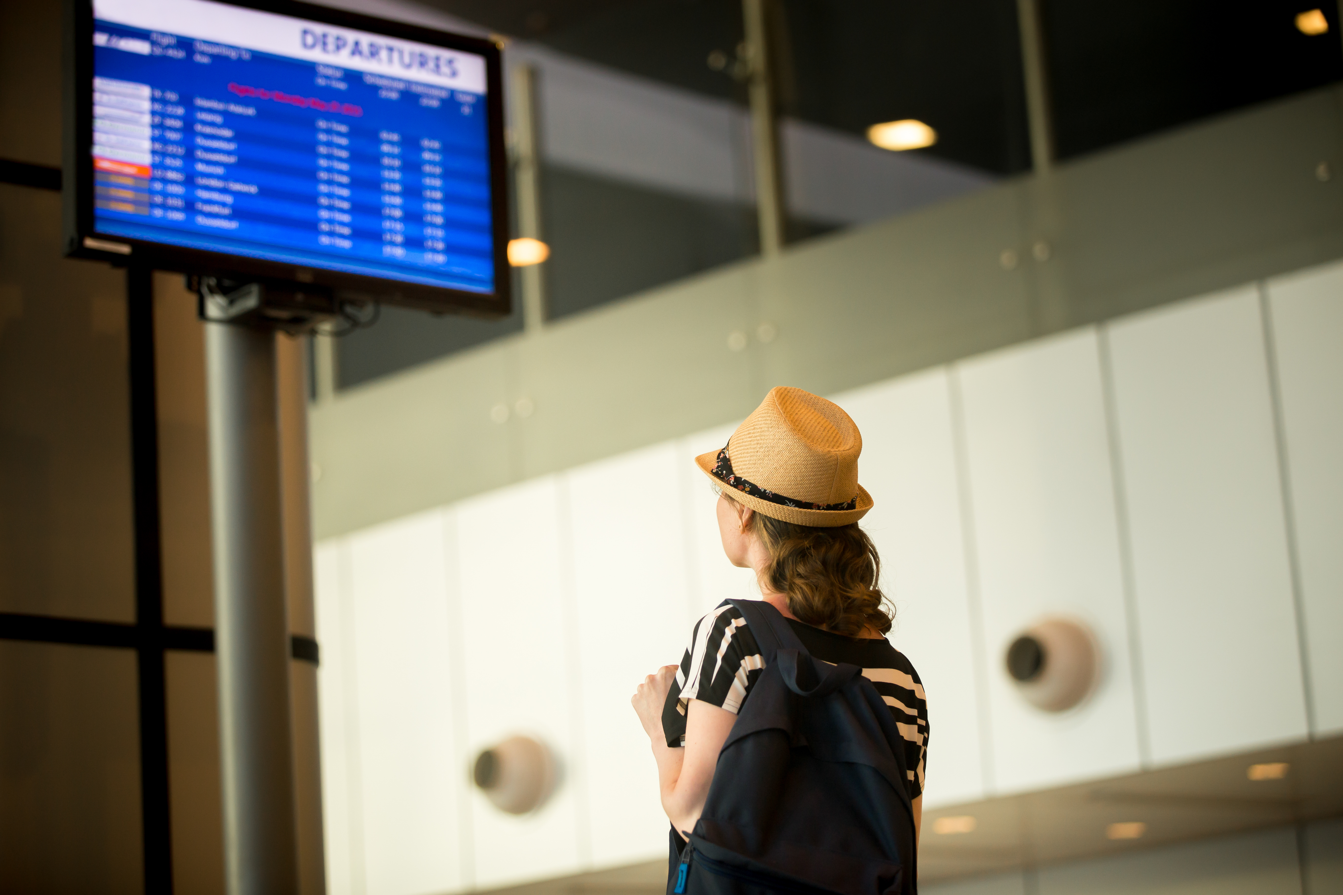 una mujer viendo el tablero de vuelos en el aeropuerto